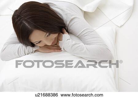 View of a young woman lying on a bed View Large Photo Image Stock Photograph - View of a young woman lying on a bed. Fotosearch