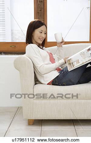 View of a young woman sitting on a sofa View Large Photo Image Stock Image - View of a young woman sitting on a sofa. Fotosearch