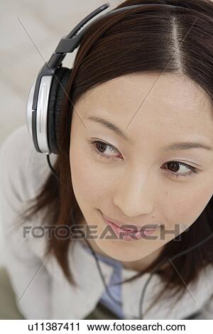 Stock Image - View of a young woman using headphone. Fotosearch