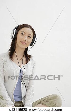 Stock Photo - View of a young woman using headphone. Fotosearch