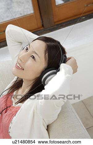 Young woman listening to music on a headphone View Large Photo Image Picture - Young woman listening to music on a headphone. Fotosearch