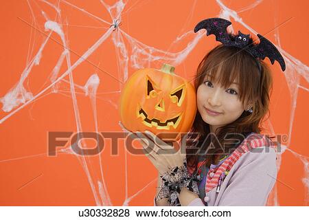 Portrait of teenage girl holding jack-o-lantern View Large Photo Image Stock Photo - Portrait of teenage girl holding jack-o-lantern. Fotosearch