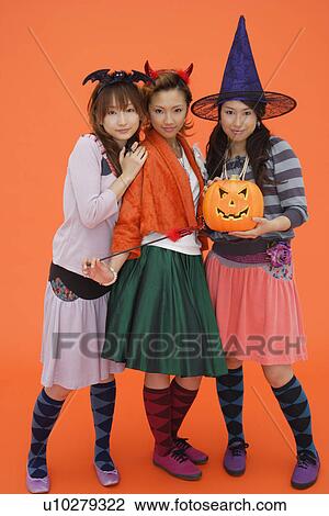 Stock Image - Teenage girls with jack-o-lantern. Fotosearch