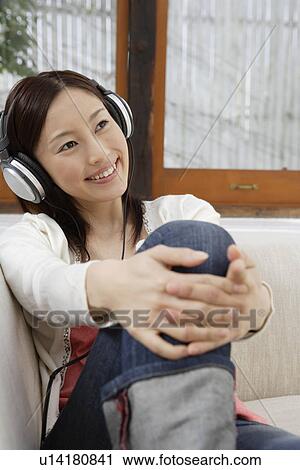 Stock Image - A young woman using headphone. Fotosearch