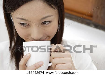 Picture - Close-up of a young woman holding a cup. Fotosearch