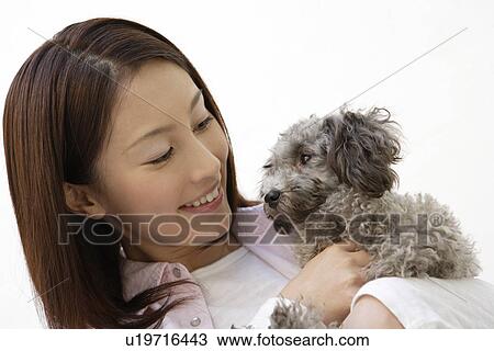 Stock Image - Close-up of a young woman holding a dog. Fotosearch
