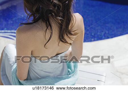 Stock Photograph - Elevated view of a woman sitting beside swimming pool. Fotosearch