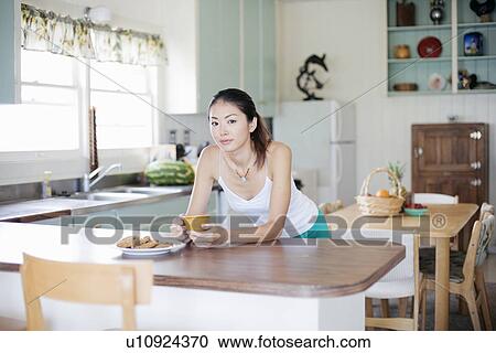 Stock Image - Portrait of a young woman at breakfast table. Fotosearch