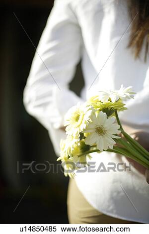 Rear view of a young woman holding flowers View Large Photo Image Stock Photography - Rear view of a young woman holding flowers. Fotosearch