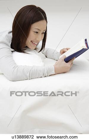 Stock Image - View of a cheerful woman reading a book. Fotosearch