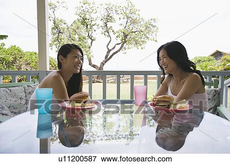 Stock Photo - Young women smiling sitting on chairs. Fotosearch