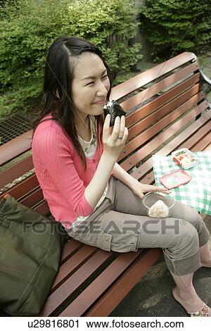 A young woman has her snacks from her lunch box and smiles while sitting on the bench View Large Photo Image Stock Image - A young woman has her snacks from her lunch box and smiles while sitting on the bench. Fotosearch