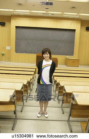 Stock Image - A young woman standing on a staircase in classroom. Fotosearch