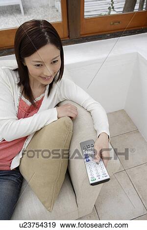 Stock Photo - Elevated view of a young woman holding a remote control. Fotosearch
