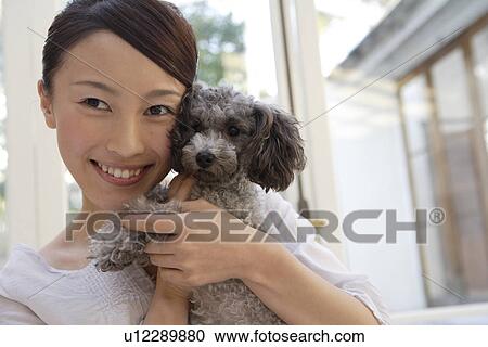 View of a young woman holding a dog View Large Photo Image Stock Image - View of a young woman holding a dog. Fotosearch