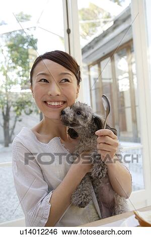 Stock Photograph - View of a young woman holding a dog. Fotosearch