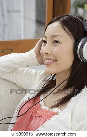 View of a young woman listening to music View Large Photo Image Stock Photography - View of a young woman listening to music. Fotosearch