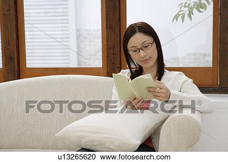 Stock Image - View of a young woman reading a book. Fotosearch