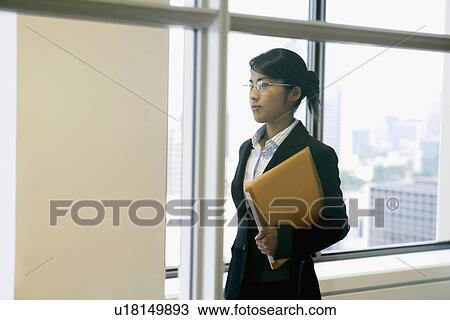 A side view of a professional woman holding a file View Large Photo Image Stock Image - A side view of a professional woman holding a file. Fotosearch