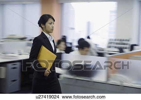 A side view of a woman holding a file moves on in the office View Large Photo Image Picture - A side view of a woman holding a file moves on in the office. Fotosearch