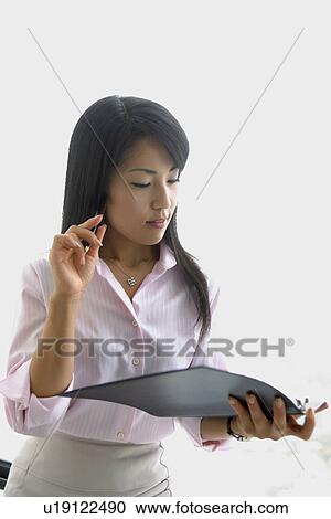 Stock Image - A woman holding a file and a pen lost in her thoughts. Fotosearch