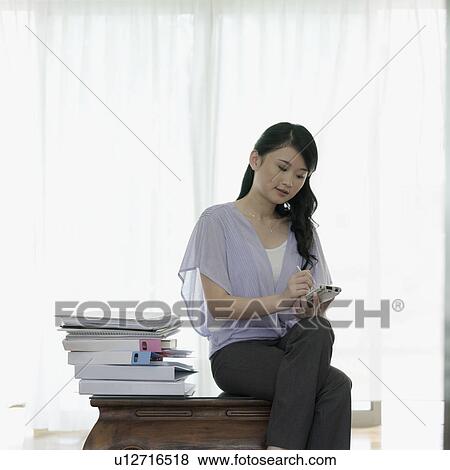 Stock Photo - Businesswoman operating a hand held device with a stylus. Fotosearch