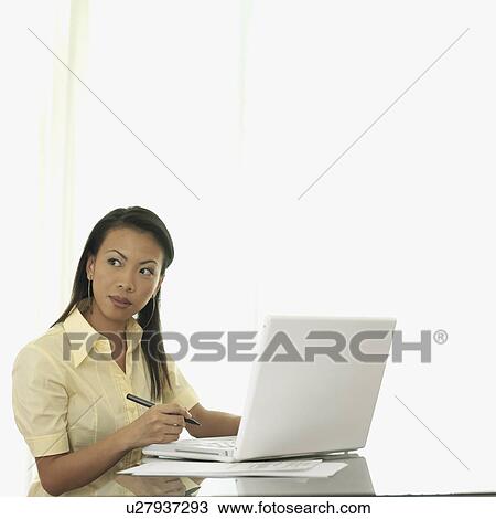 Stock Image - Businesswoman sitting in front of a laptop. Fotosearch