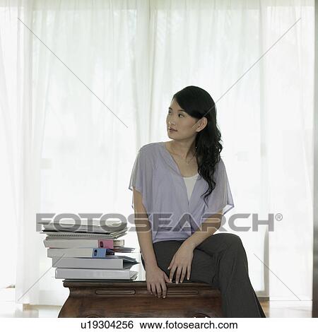 Businesswoman sitting on a table with her legs crossed View Large Photo Image Stock Photograph - Businesswoman sitting on a table with her legs crossed. Fotosearch