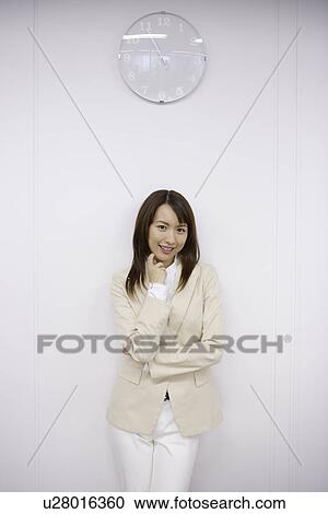 Stock Image - Businesswoman under a clock, portrait. Fotosearch