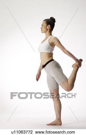 Side view of a young woman balancing on one leg View Large Photo Image Stock Image - Side view of a young woman balancing on one leg. Fotosearch