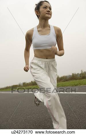 Side view of a young woman jogging on the road View Large Photo Image Stock Image - Side view of a young woman jogging on the road. Fotosearch