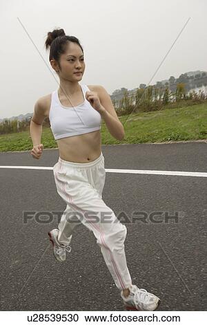 Side view of a young woman jogging on the road View Large Photo Image Stock Image - Side view of a young woman jogging on the road. Fotosearch