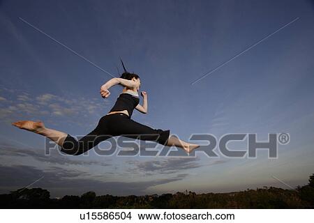 Picture - View of a young woman jumping in the air. Fotosearch