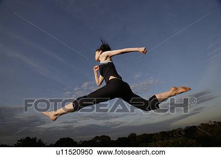View of a young woman jumping in the air View Large Photo Image Stock Image - View of a young woman jumping in the air. Fotosearch