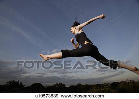 View of a young woman jumping in the air View Large Photo Image Stock Photo - View of a young woman jumping in the air. Fotosearch