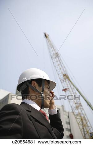 Stock Image - Businessman with a hard hat, portrait. Fotosearch