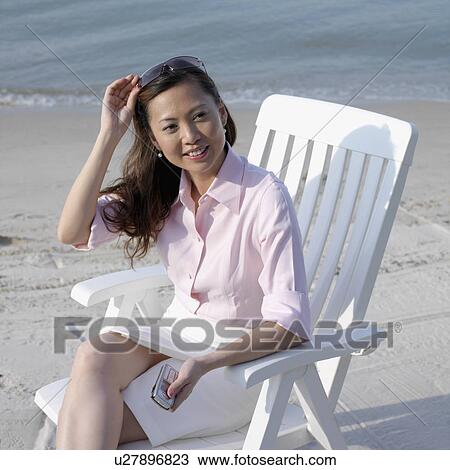 Stock Image - High angle view of a mid adult woman sitting on the beach. Fotosearch