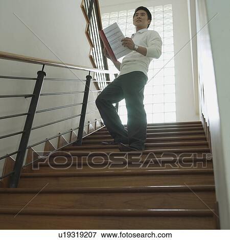 Stock Photo - Low angle view of a businessman holding a file. Fotosearch