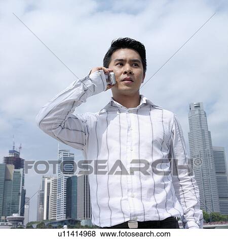 Low angle view of a businessman talking on a mobile phone View Large Photo Image Stock Photo - Low angle view of a businessman talking on a mobile phone. Fotosearch