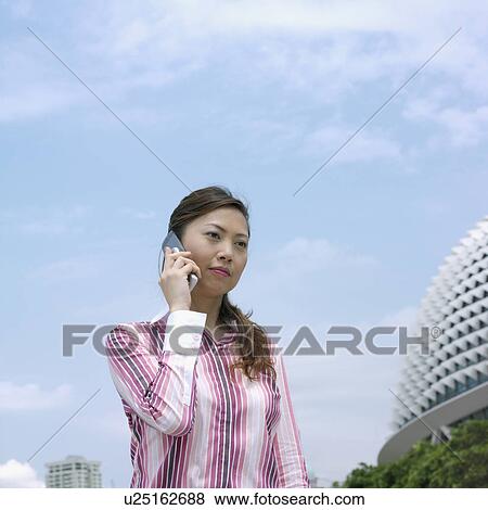 Stock Photo - Low angle view of a mid adult woman talking on a mobile phone. Fotosearch