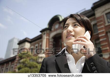 Stock Photography - Low angle view of a young woman using mobile phone. Fotosearch