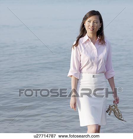 Stock Photo - Mid adult woman standing on the beach. Fotosearch