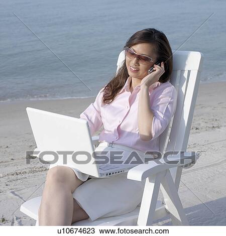 Mid adult woman talking on a mobile phone at the beach View Large Photo Image Stock Image - Mid adult woman talking on a mobile phone at the beach. Fotosearch