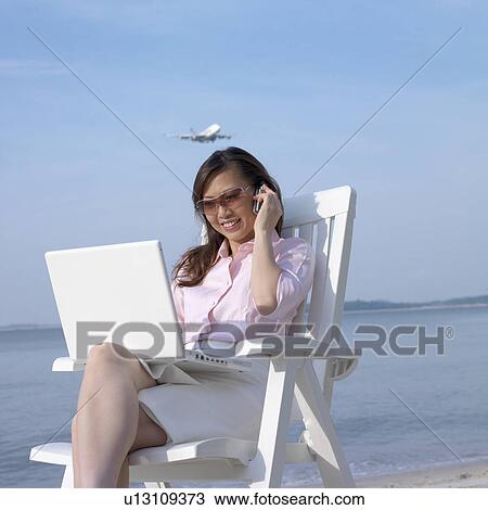 Mid adult woman talking on a mobile phone at the beach View Large Photo Image Stock Image - Mid adult woman talking on a mobile phone at the beach. Fotosearch