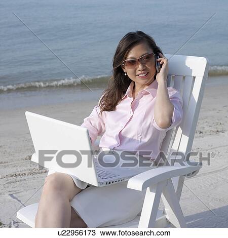 Mid adult woman talking on a mobile phone at the beach View Large Photo Image Stock Image - Mid adult woman talking on a mobile phone at the beach. Fotosearch