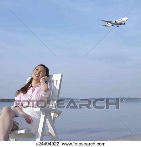 Mid adult woman talking on a mobile phone at the beach View Large Photo Image Stock Image - Mid adult woman talking on a mobile phone at the beach. Fotosearch