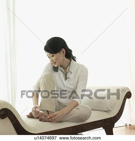 Stock Photo - Young woman painting her toe nails. Fotosearch