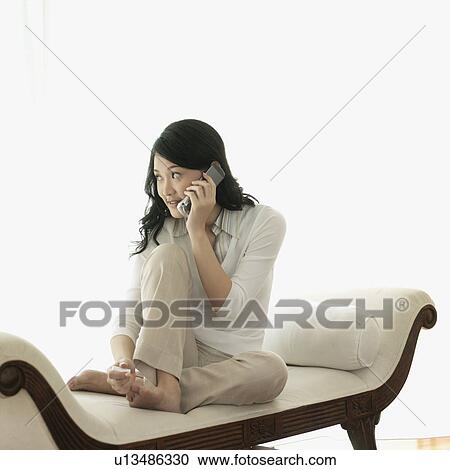 Young woman talking on a mobile phone and painting her toe nails View Large Photo Image Stock Image - Young woman talking on a mobile phone and painting her toe nails. Fotosearch