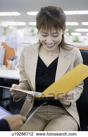 Stock Image - A woman reading a file with full of ecstasy. Fotosearch