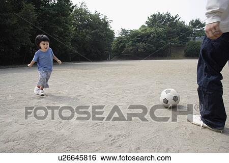 Stock Photograph - A boy playing football with his father. Fotosearch